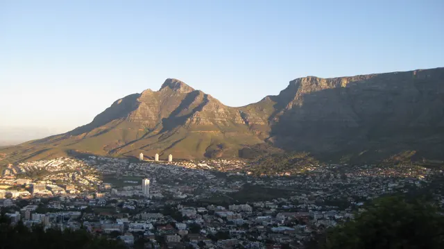 Golden mountain faces overlook dense city roofs.