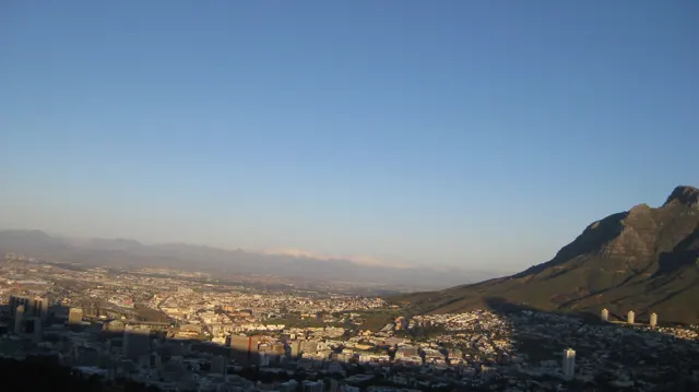 A broad shadow falls across the foreground city in evening light.