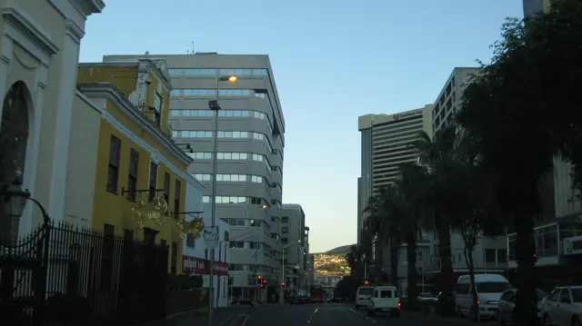Older facades stand beside taller office buildings along a street.
