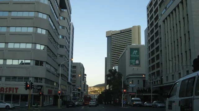 A city street runs between tall windowed office buildings.