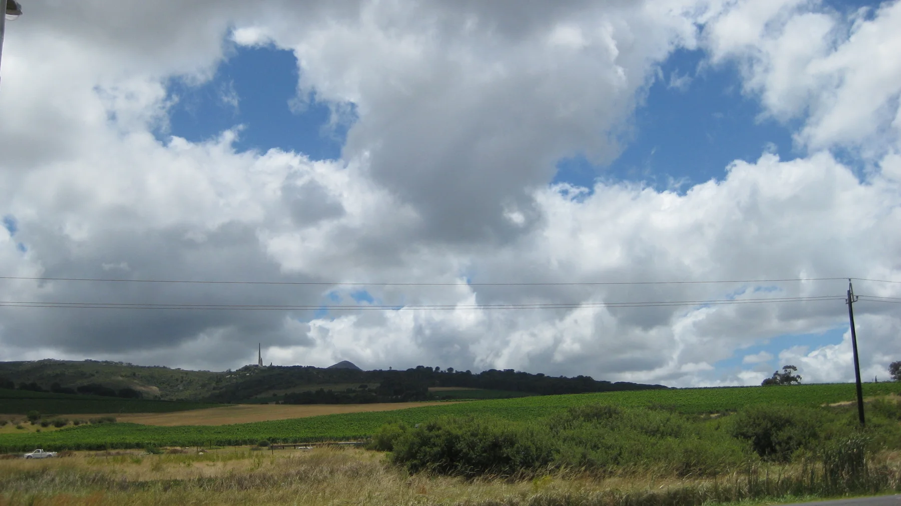 Open fields stretch beneath a sky filled with towering clouds.