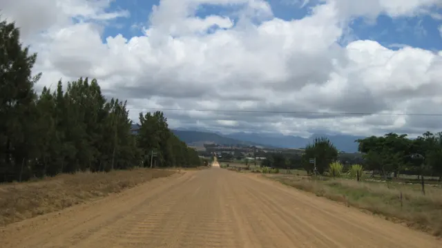 A wide dirt road leads into a valley beneath layered clouds.