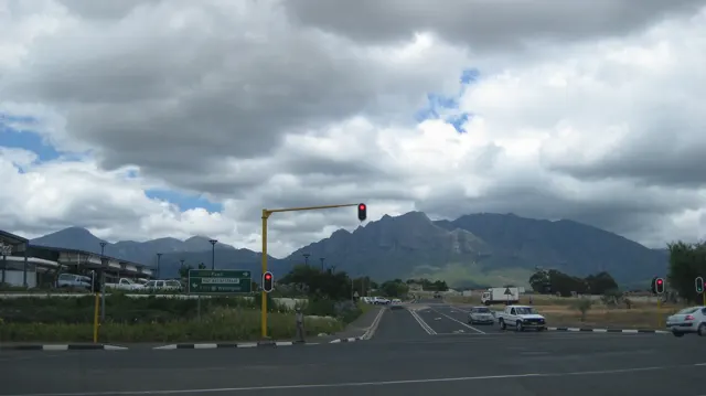 Traffic lights stand at a town junction beneath dark mountains.