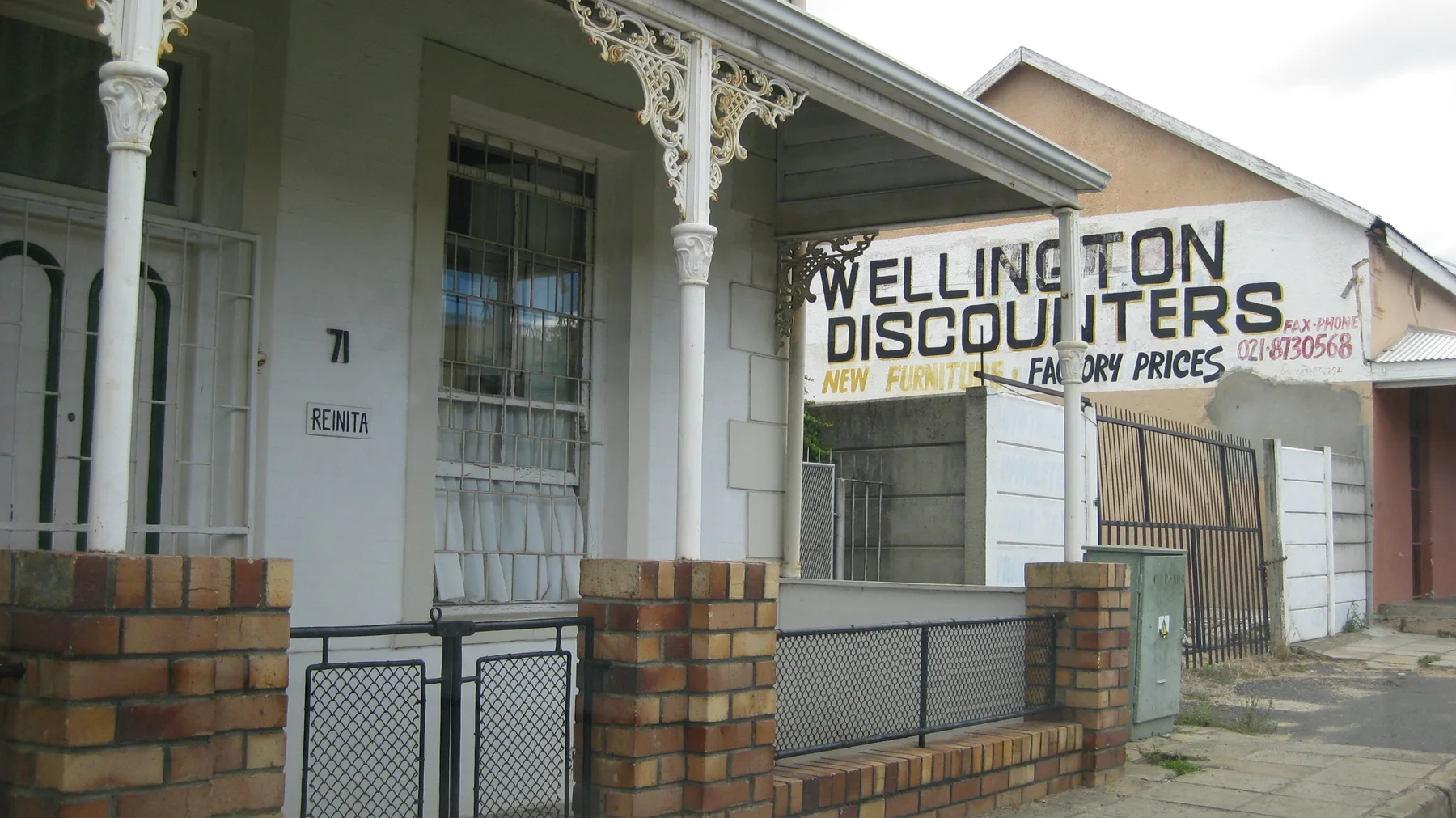A painted shop sign hangs beneath decorative veranda supports.