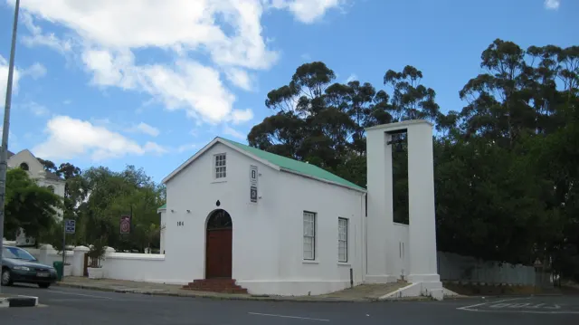 A small white church has a green-edged roof and simple bell tower.