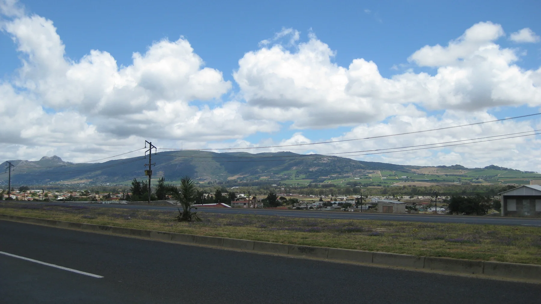 Large white clouds rise above low development and distant mountains.