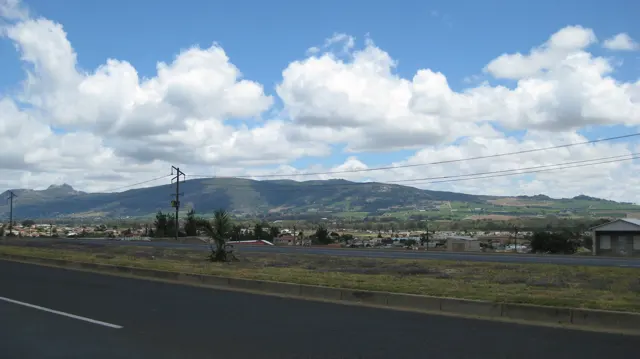 Large white clouds rise above low development and distant mountains.