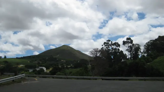 A green hill rises beyond a curving guardrail.
