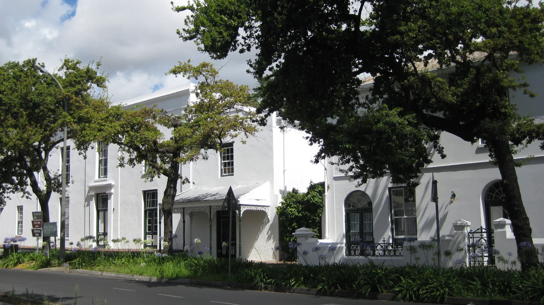 White building facades stand behind large shade trees.