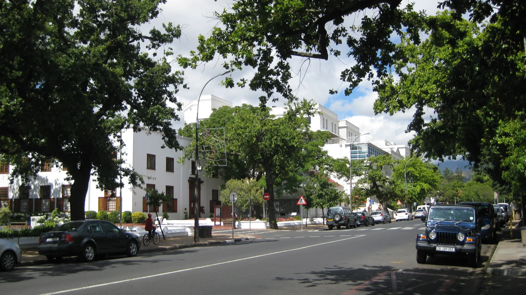Leafy trees shade a broad avenue lined with pale buildings.