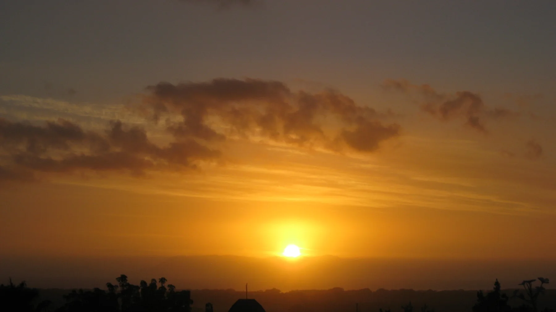 Golden light fills the sky above a low sun and dark horizon.