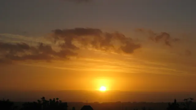 Golden light fills the sky above a low sun and dark horizon.
