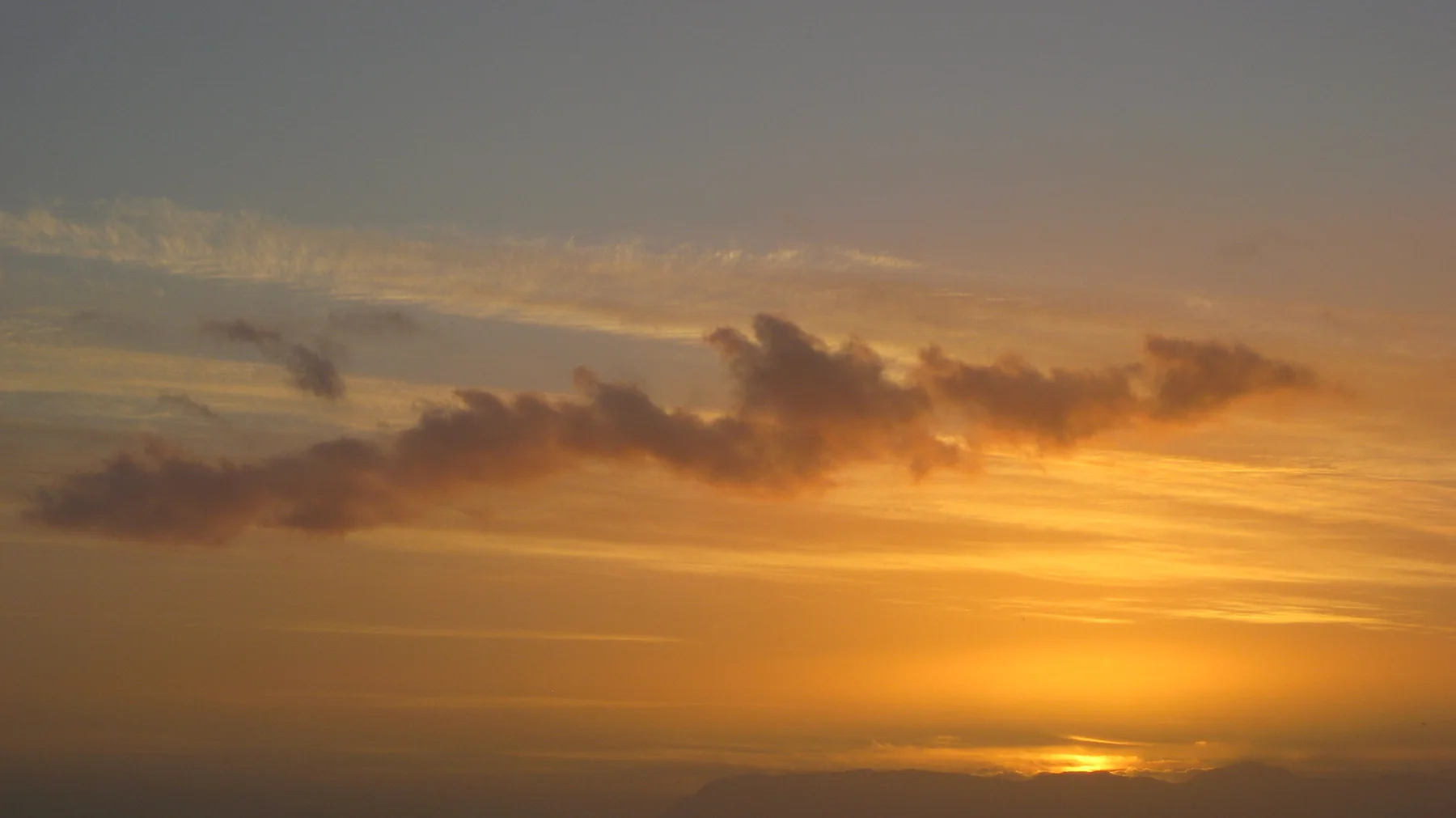 Thin golden cloud layers stretch beneath darker cloud shapes.
