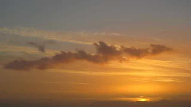 Thin golden cloud layers stretch beneath darker cloud shapes.