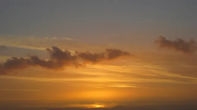 Orange streaks light the sky beneath a dark cloud band.