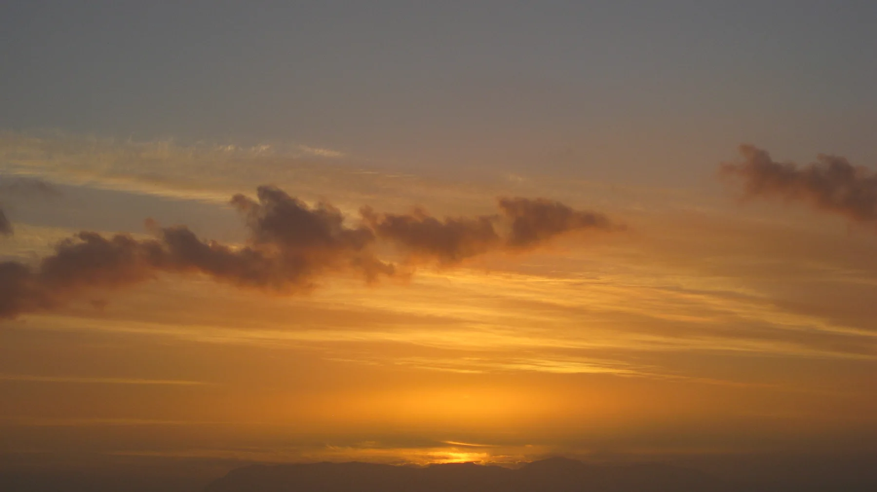 Golden light fades near the horizon below scattered clouds.