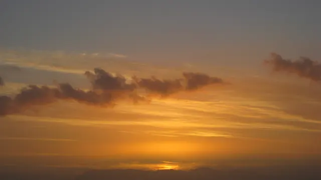 Golden light fades near the horizon below scattered clouds.