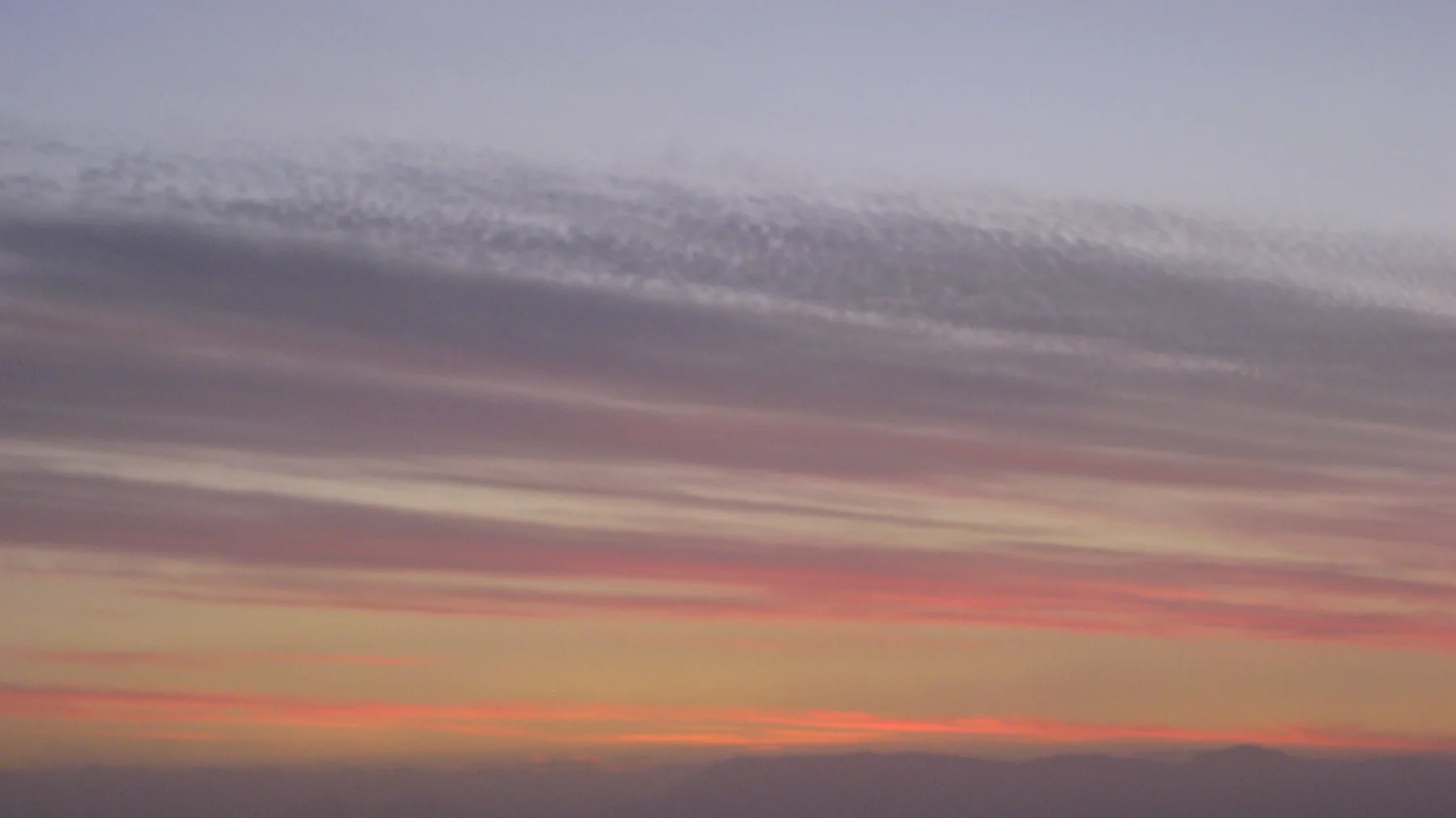 Soft pink layers brighten the horizon beneath gray-purple clouds.
