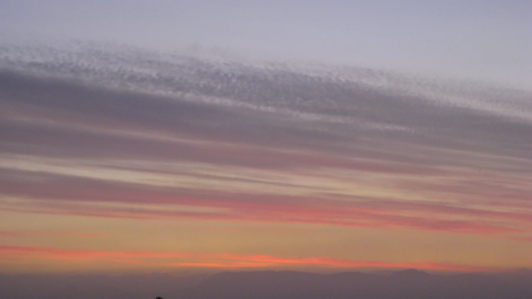 A coral-colored ribbon of light runs below muted cloud bands.