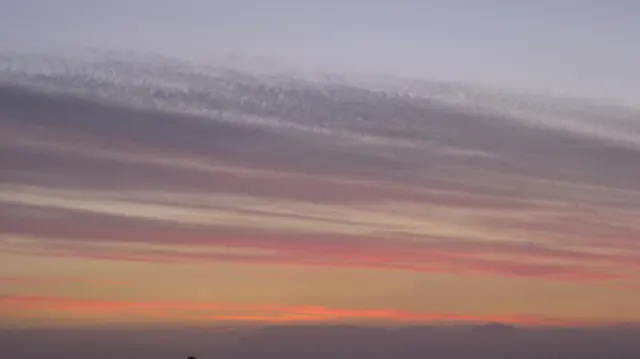 A coral-colored ribbon of light runs below muted cloud bands.