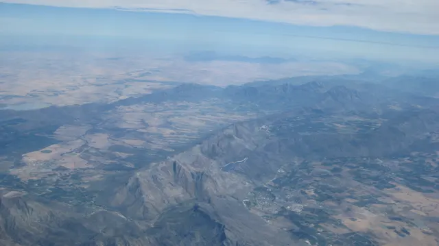 Fields and mountains form a broad aerial patchwork.