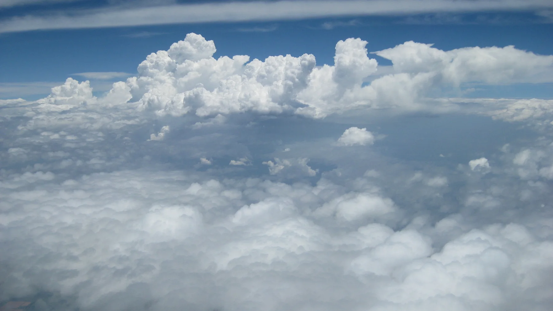 Tall white clouds rise above a lower cloud layer.