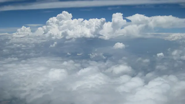 Tall white clouds rise above a lower cloud layer.