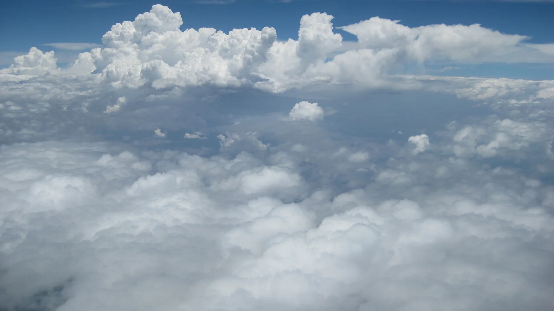 A bright bank of clouds stretches beneath deep blue sky.