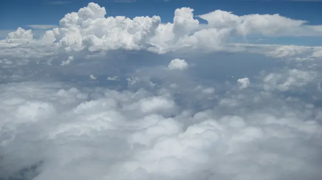 A bright bank of clouds stretches beneath deep blue sky.
