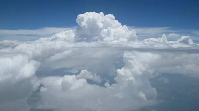 A tall white cloud rises above a lower scattered layer.