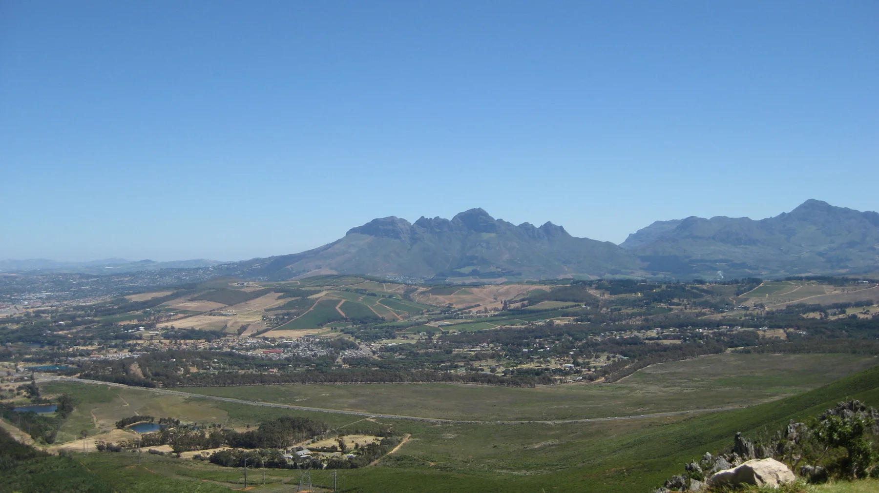 Fields and low development spread toward distant rugged peaks.
