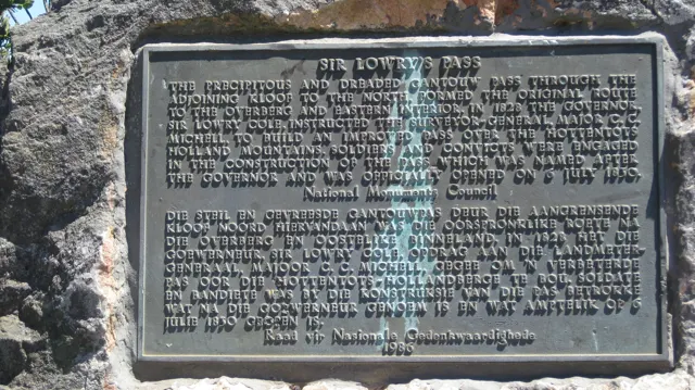 A dark historical plaque is mounted in a rough rock surface.