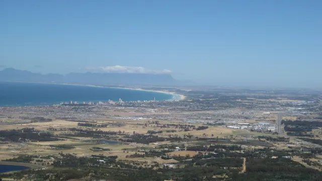 A broad bay curves beyond fields and dense low development.
