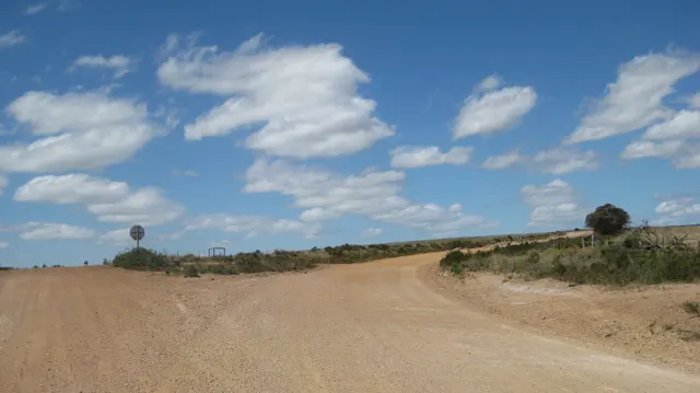 A wide gravel junction lies beneath scattered white clouds.