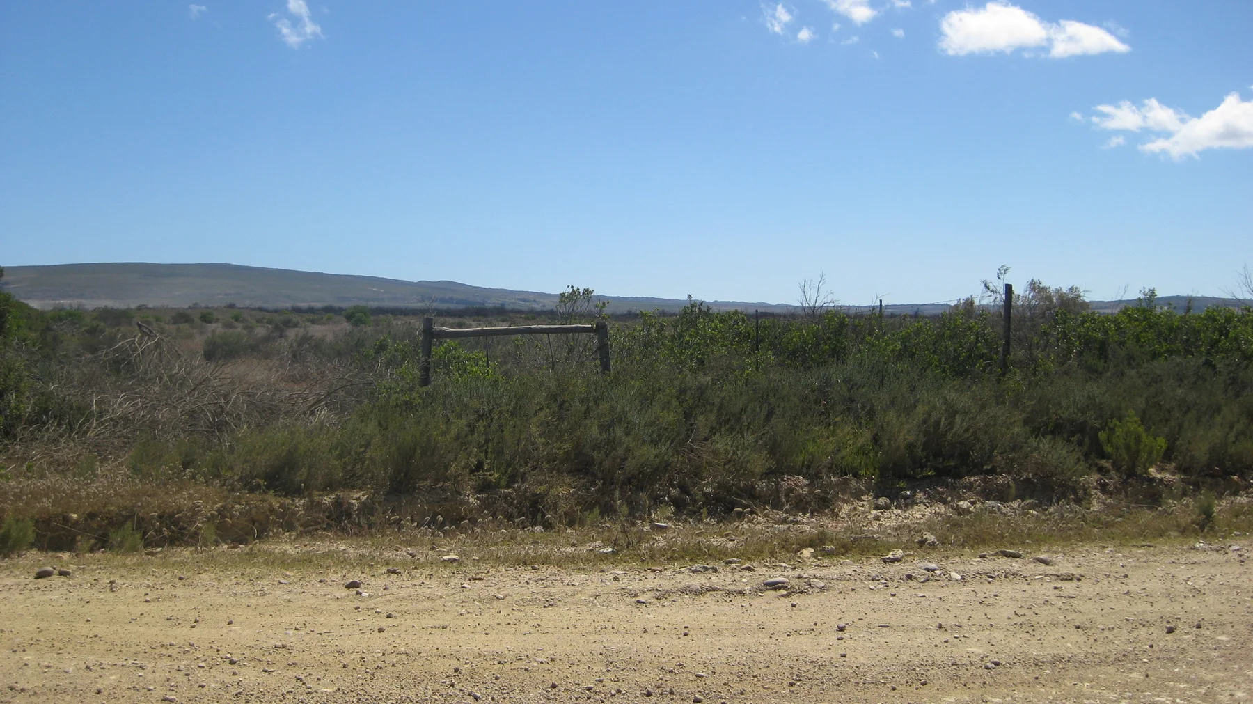 A low fence crosses scrubland below a distant ridge.