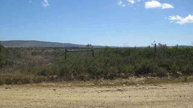 A low fence crosses scrubland below a distant ridge.