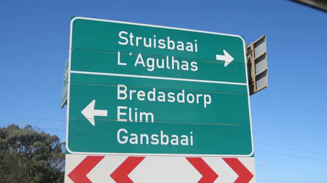 A green sign points toward Struisbaai, L'Agulhas and inland towns.