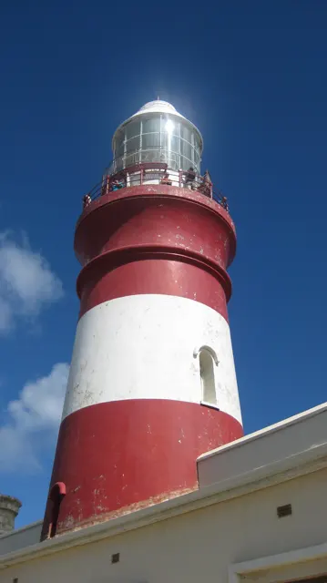 Sunlight catches the lantern atop a red-and-white tower.