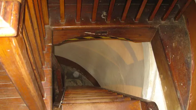 Steep wooden stairs descend through a timber-framed interior.