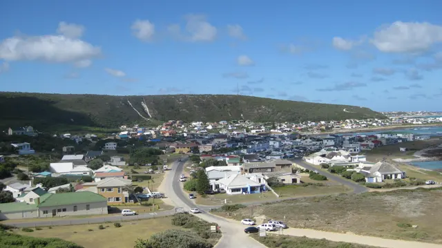 Small houses and curving roads fill a coastal town below.