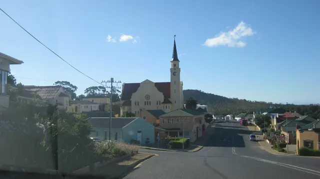 A church spire rises above a small town junction.