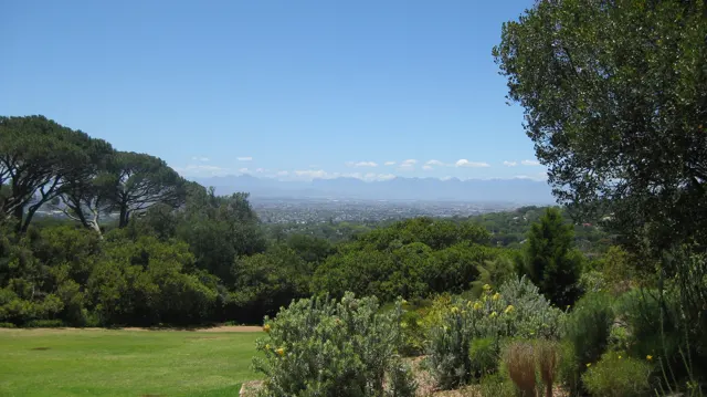 A garden lawn opens toward a distant valley between trees.