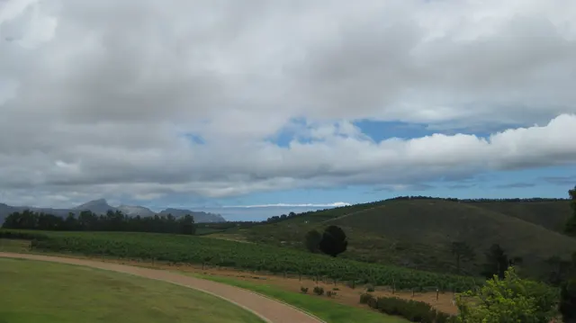 Green fields roll toward low hills beneath layered clouds.