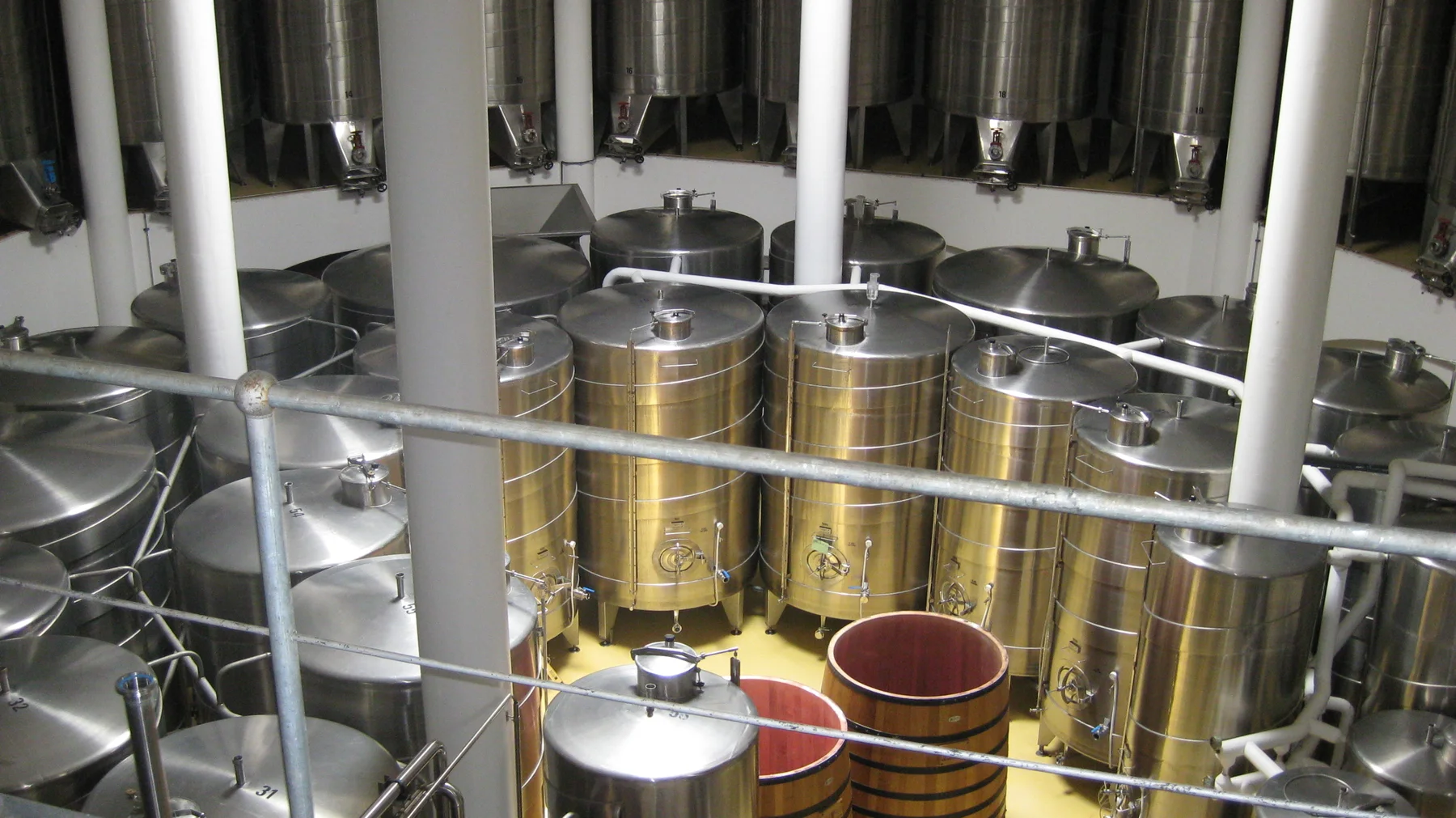 Large stainless-steel tanks fill a bright winery interior.