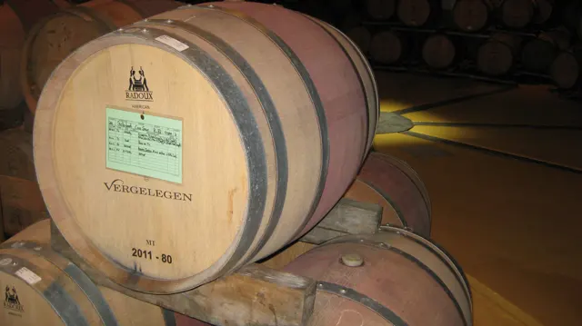 A labeled wooden barrel rests among stacked cellar barrels.