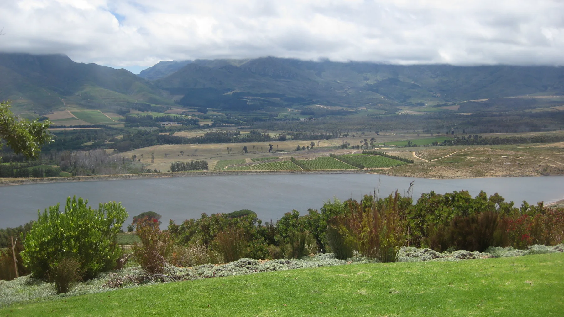 Water lies below cultivated slopes and clouded mountains.