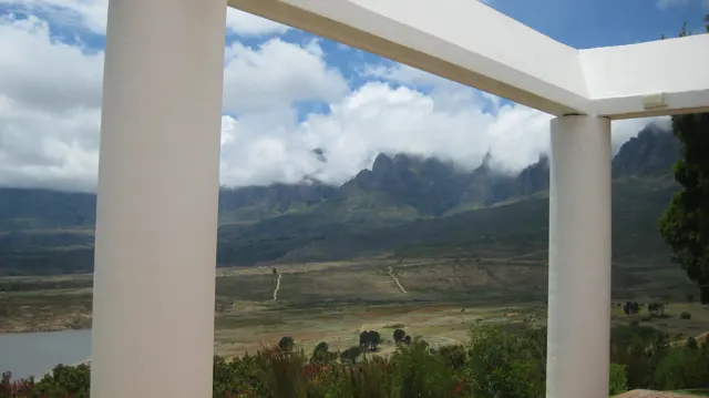 White columns frame a cloud-covered mountain view.
