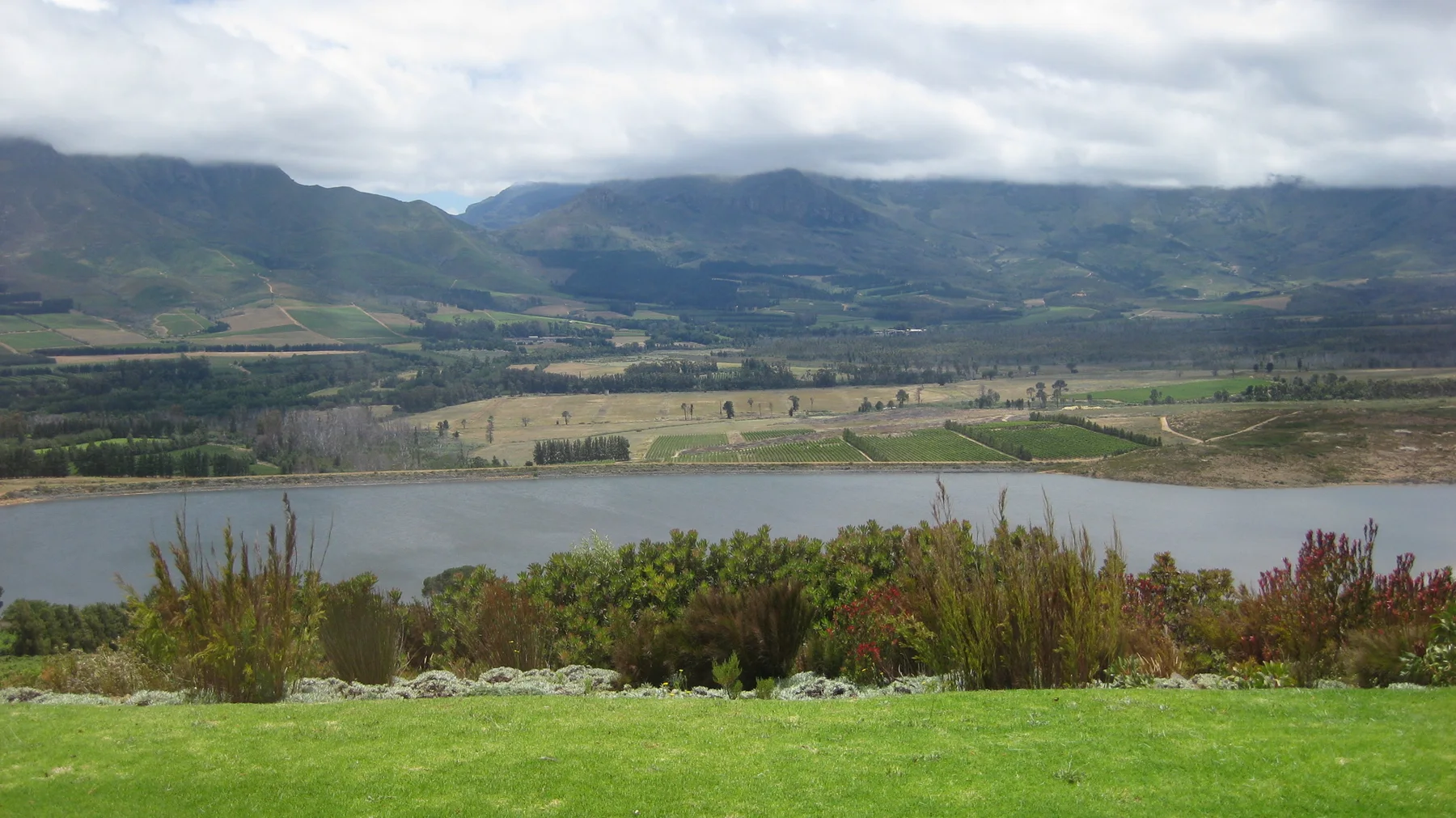 A reservoir stretches below broad cultivated mountain slopes.