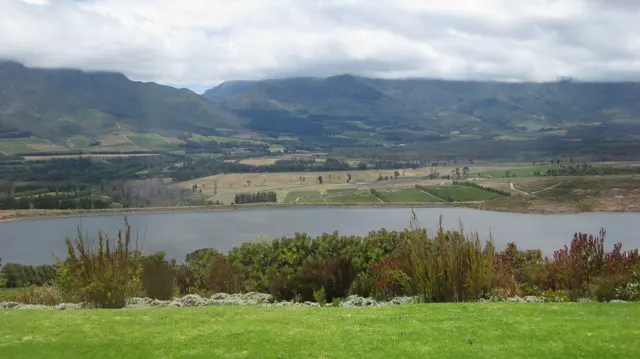 A reservoir stretches below broad cultivated mountain slopes.