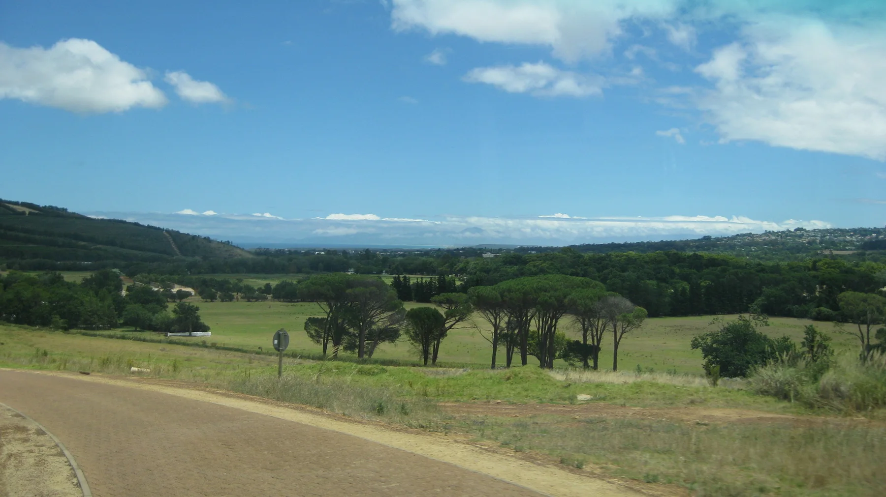 Trees and green estate grounds spread below a curving path.